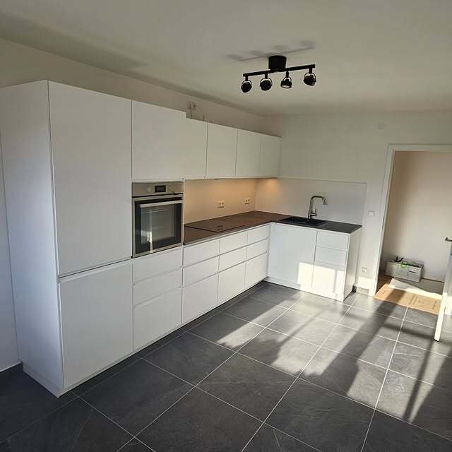 Weiße L-Küche mit dunkler Arbeitsplatte und Einbaugeräten