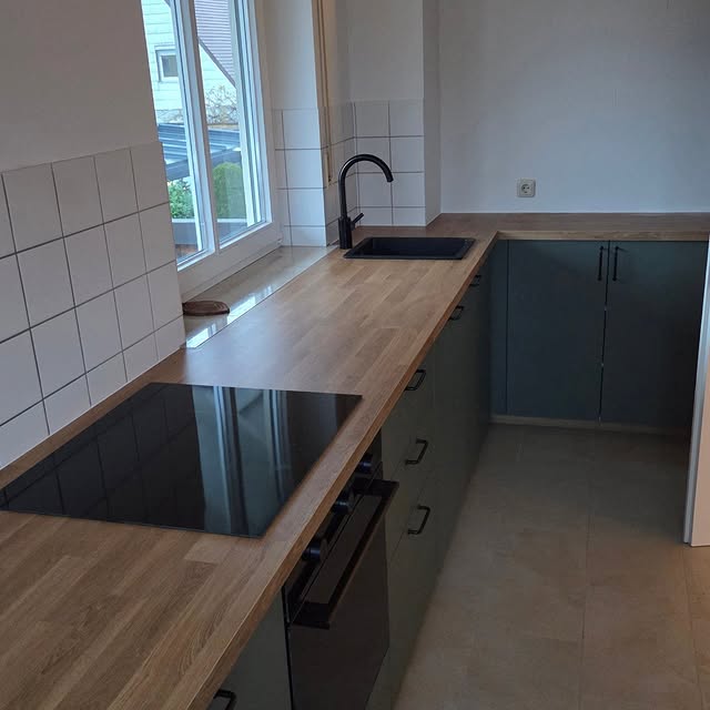 Grüne Küche mit Holzarbeitsplatte und schwarzer Armatur